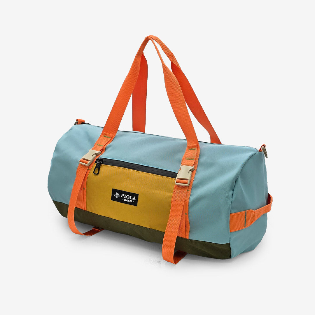 Maletín Sprint celeste con bolsillo mostaza y asas naranjas, perfecto para la ciudad y escapadas. Producto peruano con estilo urbano hecho por Piola Bags.